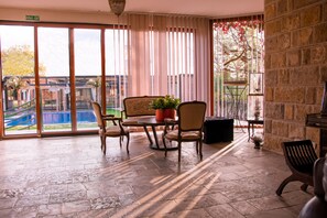 A spacious room with a large sliding glass door leading to an outdoor area, a round table with chairs, and a potted plant. - The Belgrade Hills (Belgrade)
