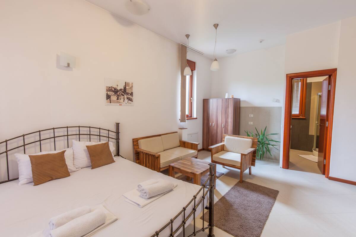 A hotel room with a bed, a sofa, a small table, and a cabinet.