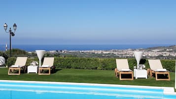 Una piscina al aire libre de temporada, sillones reclinables de piscina