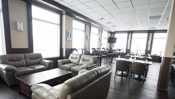 A spacious lounge area with leather sofas and armchairs, a wooden coffee table, and a dining area with tables and chairs. - Nova Inn Manning (Manning)