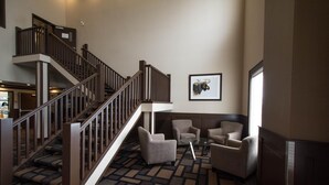 A lobby with a staircase, seating area, and a framed picture on the wall. - Nova Inn Manning (Manning)