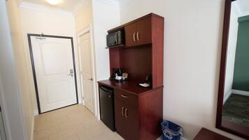 A compact kitchen with a microwave, coffee maker, and a trash bin.