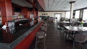 A bar area with a long counter, stools, and a variety of bottles and glasses. - Nova Inn Manning (Manning)