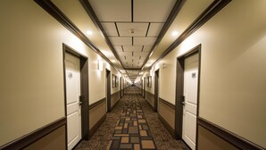 A long, narrow hotel corridor with doors numbered 231 and 234, carpeted floor, and overhead lighting. - Nova Inn Manning (Manning)