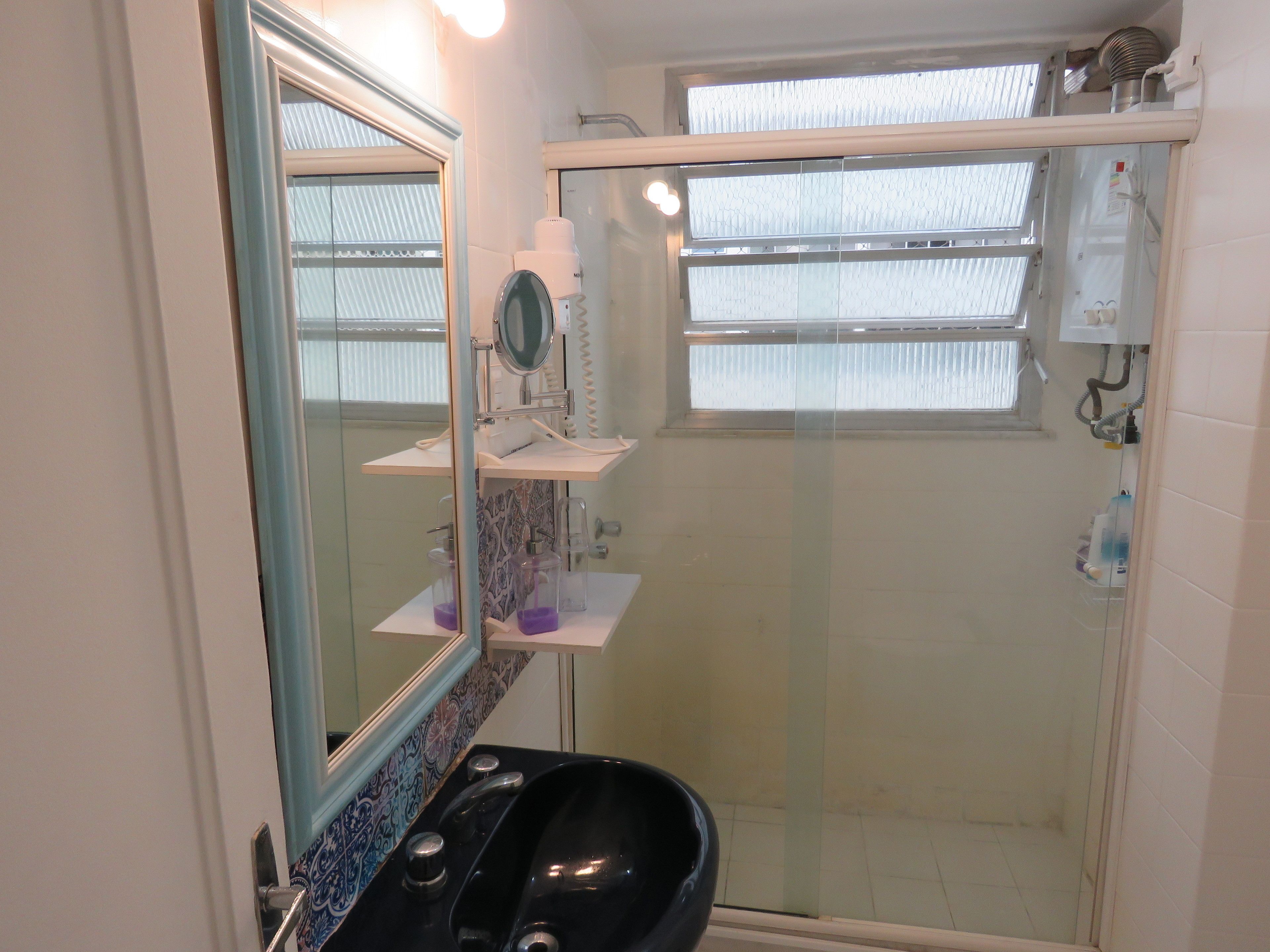 Een badkamer met een zwart wastafel, een spiegel en een douchecabine.