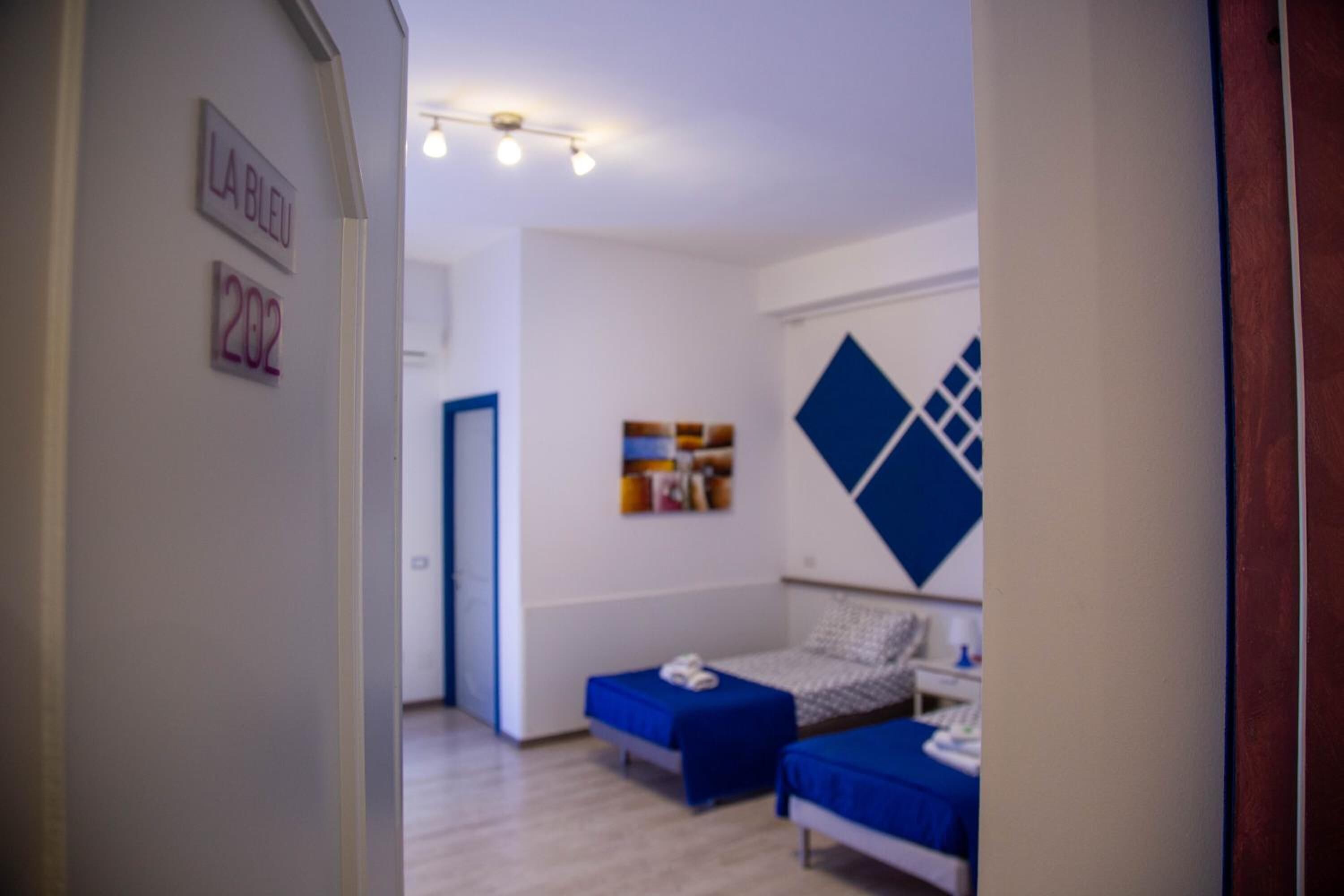 A modern hotel room with a bed, bedside table, and a wall-mounted artwork.