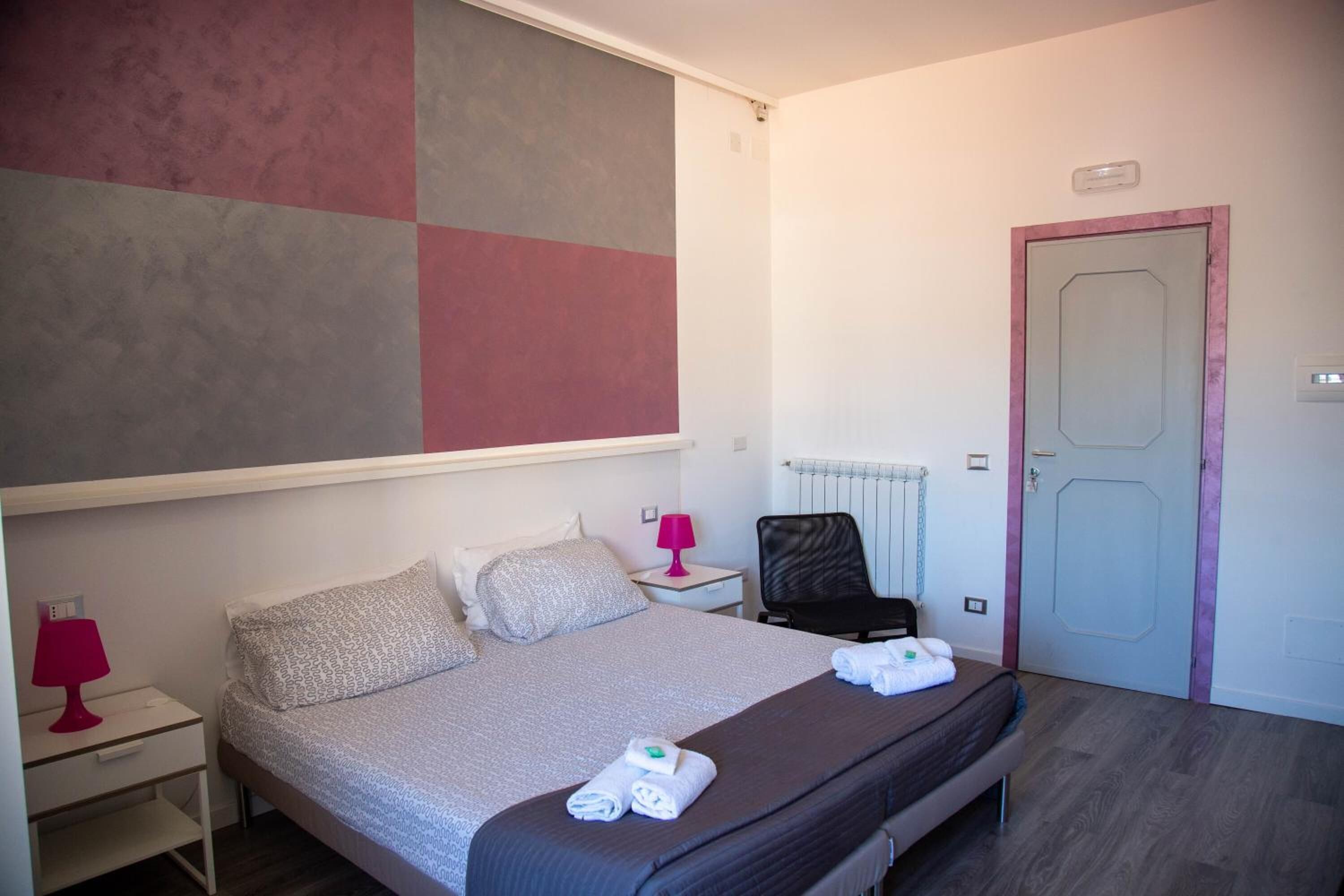 A neatly arranged hotel room with a bed, bedside tables, a chair, and a door.