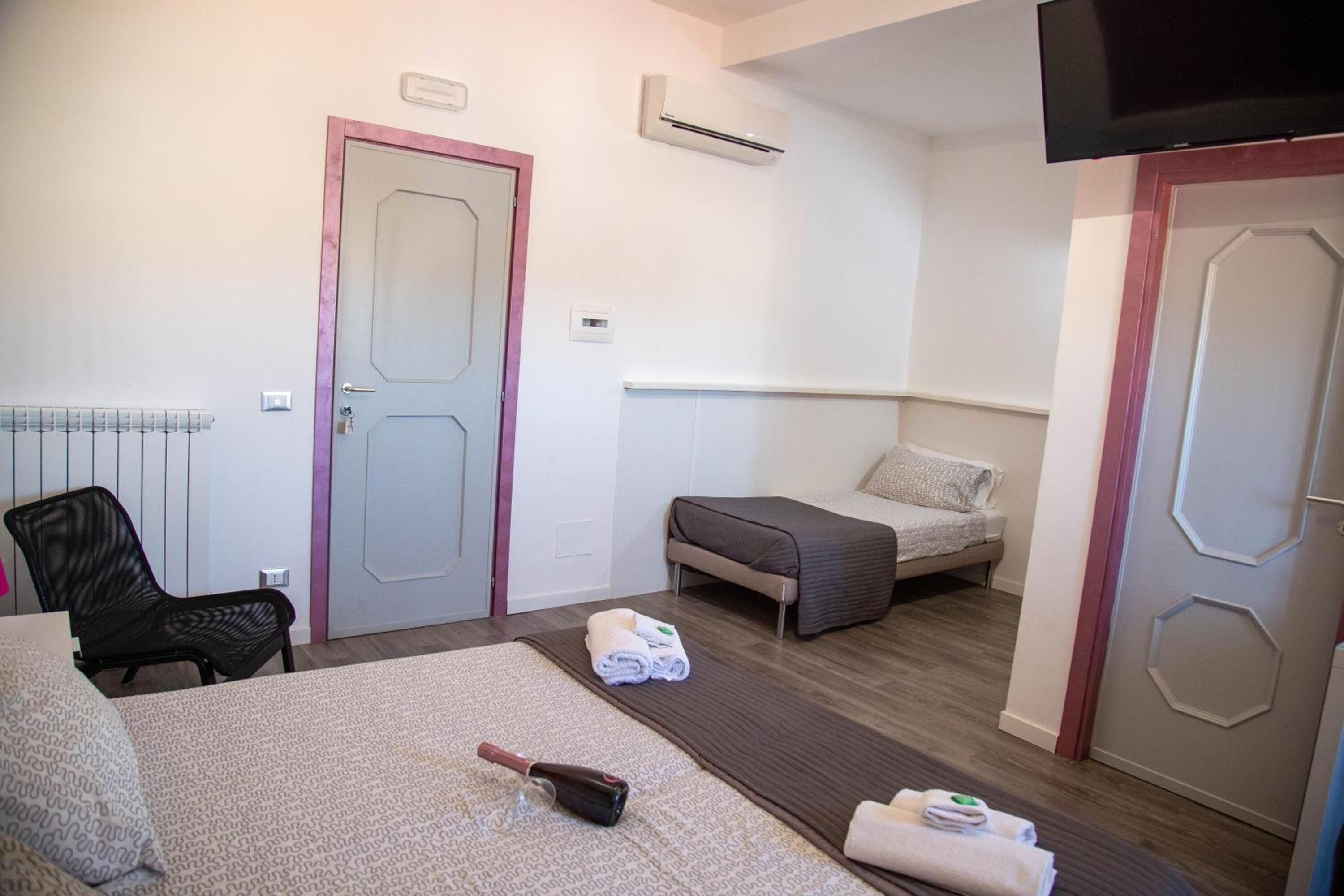 A hotel room with a bed, a chair, a sofa, and a TV.