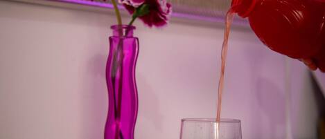 A hand pouring a red liquid from a bottle into a glass.