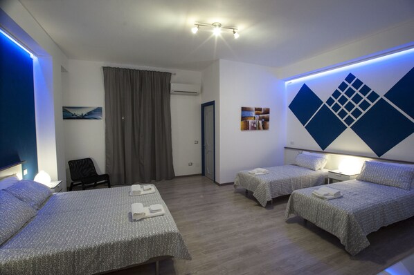 A hotel room with two single beds, a desk, a chair, and a large window with curtains.
