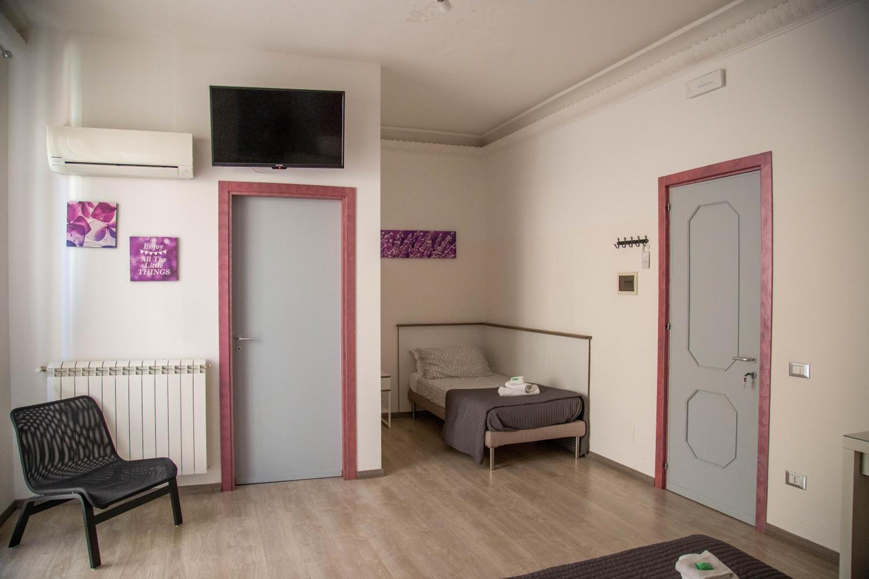 A bedroom with a bed, a chair, a television, and a door.