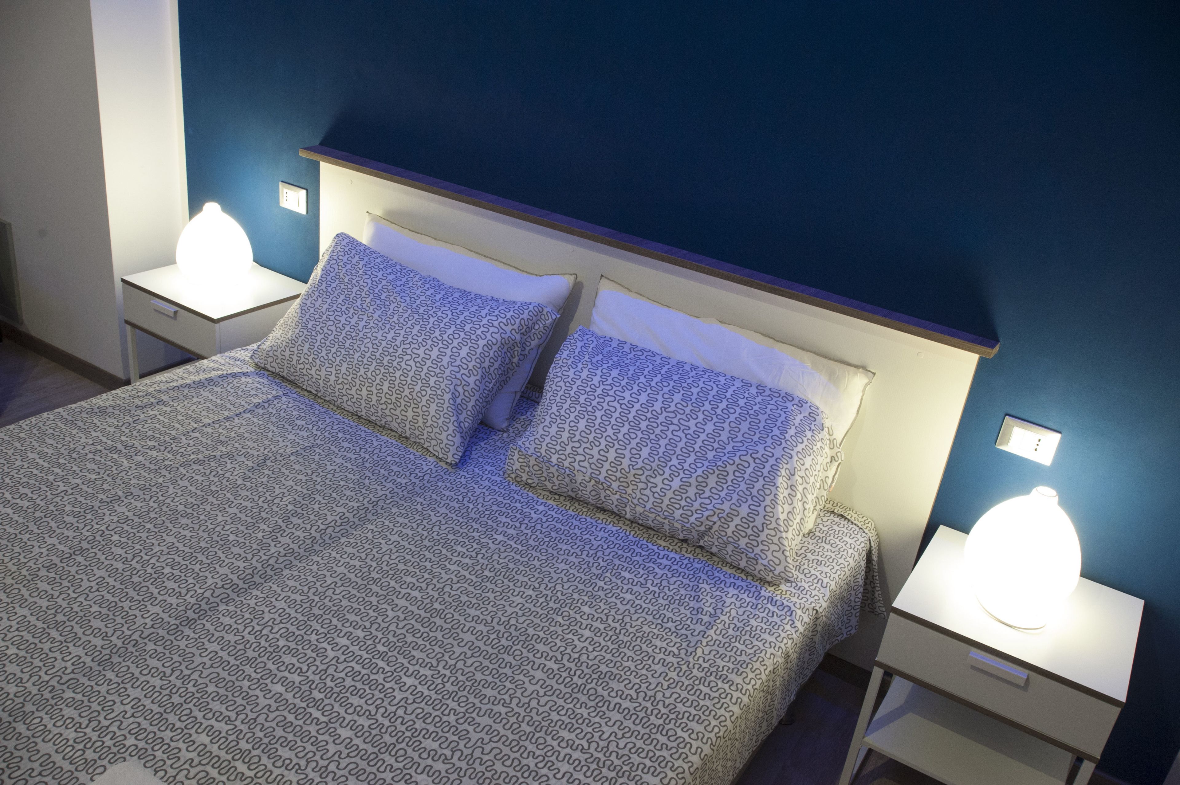 A neatly made bed with patterned bedding and two bedside lamps on white nightstands.