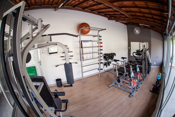 A gym with exercise equipment, a basketball hoop, and a mirror on the wall.