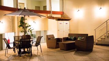 An outdoor patio with a table and chairs, a wicker sofa, and a potted plant.