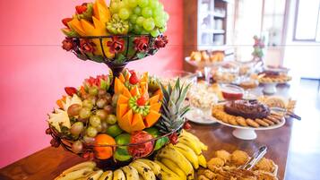 A fruit and dessert buffet with various fruits, bananas, and cookies.