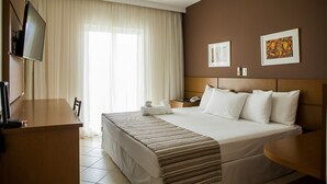 A hotel room with a bed, a desk, a TV, and a window with curtains. - Mundial Parque Hotel (Vicosa)