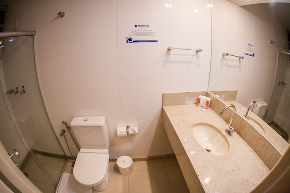 A bathroom with a toilet, sink, and shower. There are signs on the wall and a roll of toilet paper on the floor. - Mundial Parque Hotel (Vicosa)