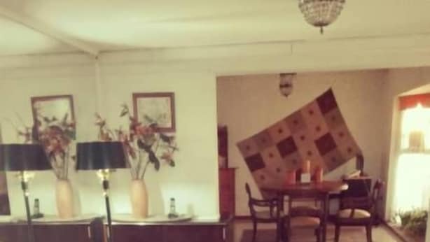 Uma sala de estar espaçosa com sofá, mesa de jantar e cadeiras, além de um lustre.