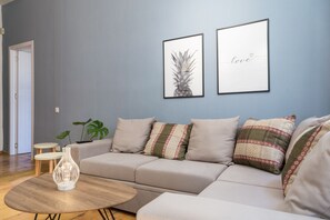 A modern living room with a grey sofa, a round wooden coffee table, and two framed pictures on the wall. - Gallery Hostel Tbilisi (Tbilisi)