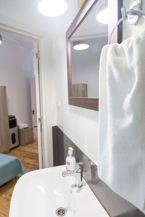 A bathroom with a white sink, a mirror, and a towel hanging on a rack. - Gallery Hostel Tbilisi (Tbilisi)