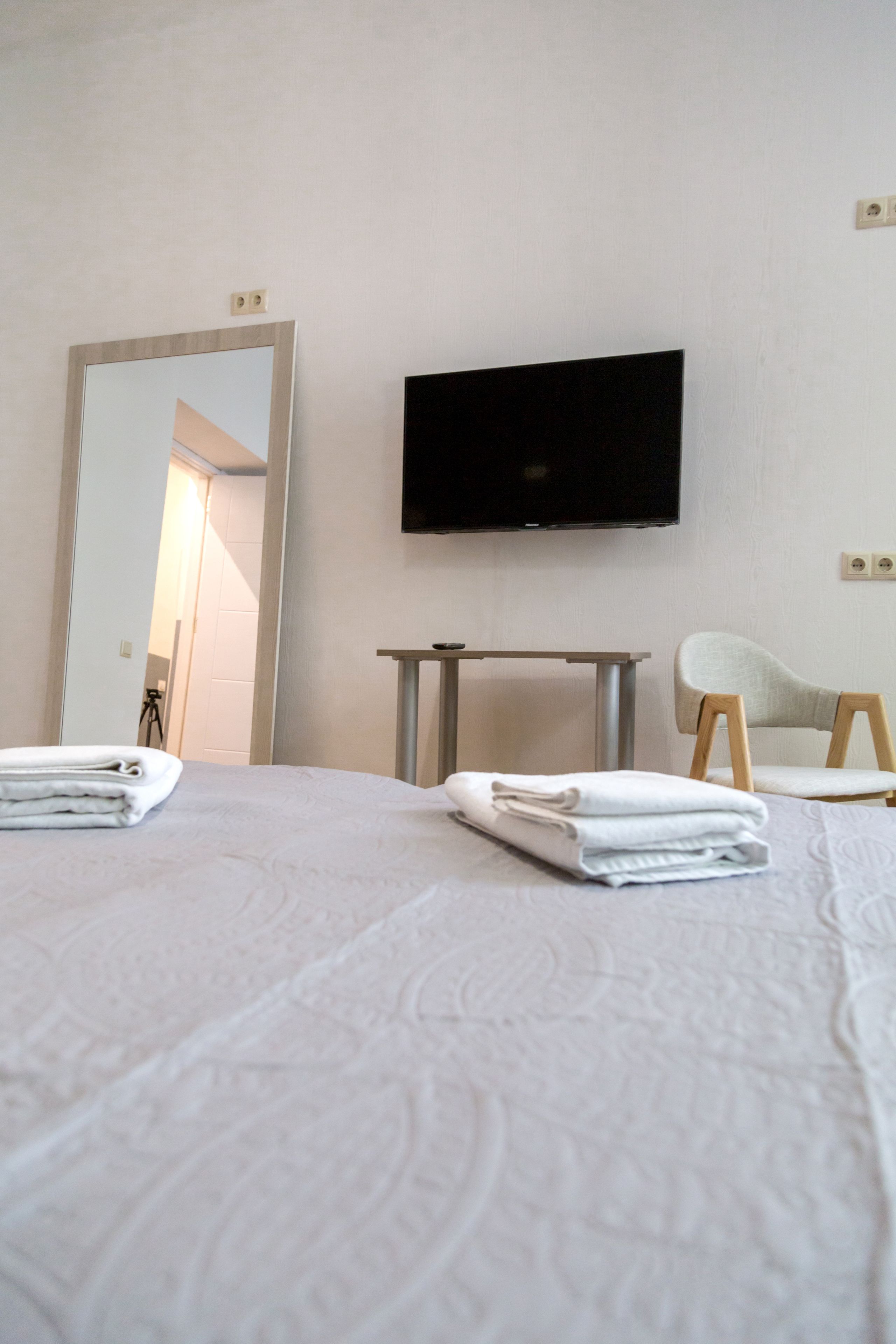 A hotel room with a bed, a TV mounted on the wall, a chair, and a table.