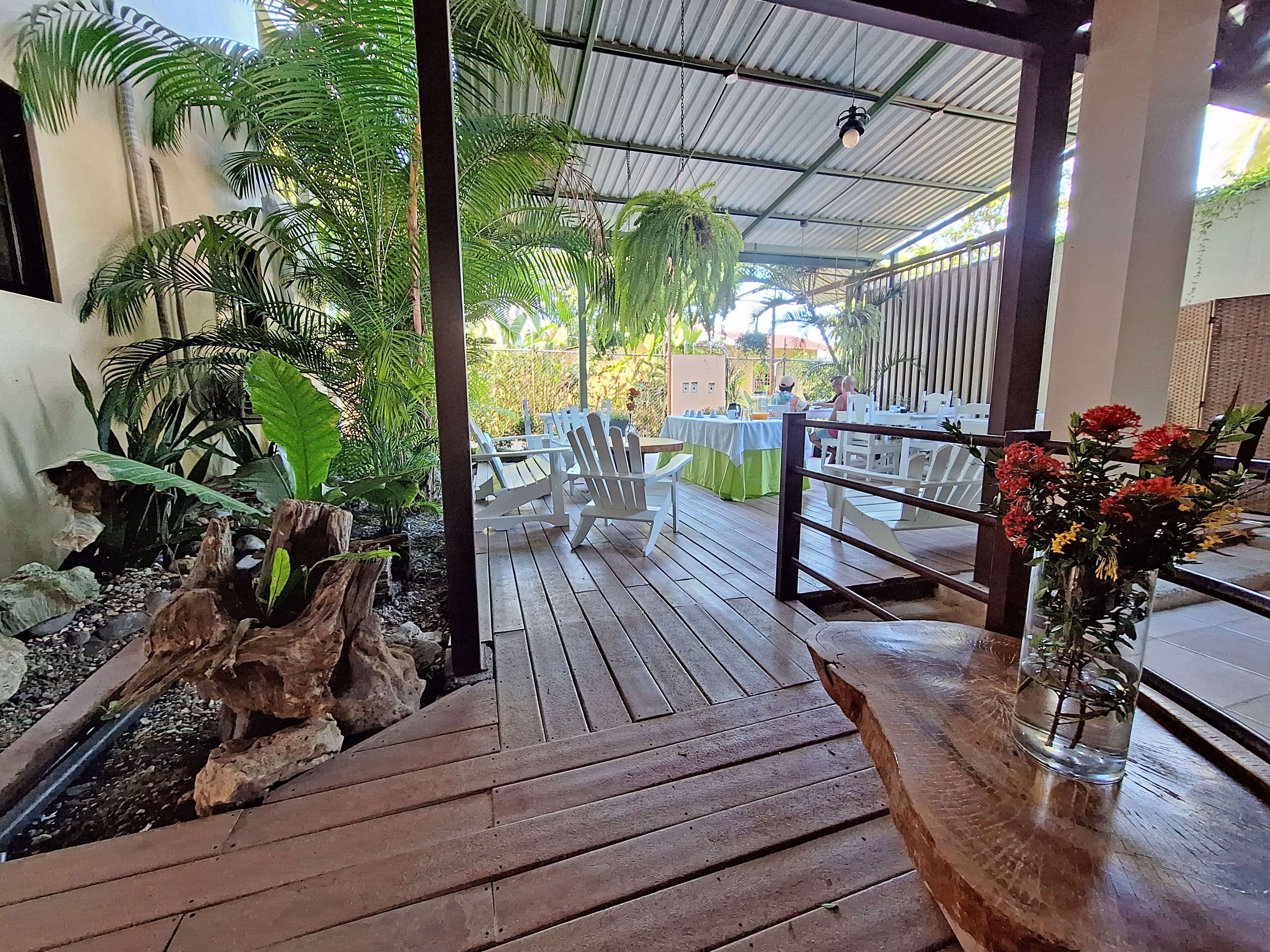 A wooden deck with outdoor seating, surrounded by lush greenery and a rustic stone feature.