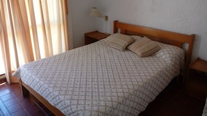 Ein Schlafzimmer mit einem Bett, zwei Nachttischen, einem Fenster mit Vorhängen.