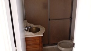 Ein kleines Badezimmer mit einem Holzbettchen, einem Waschbecken und einer Toilette.