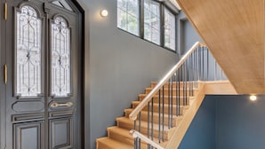 A staircase with wooden steps and metal railings, leading to a landing with a dark blue wall and a window.