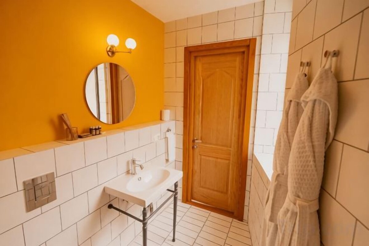 A bathroom with a white sink, a round mirror, and a wooden door.