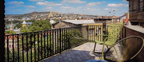 A balcony with a view of a cityscape, including buildings and a hill.