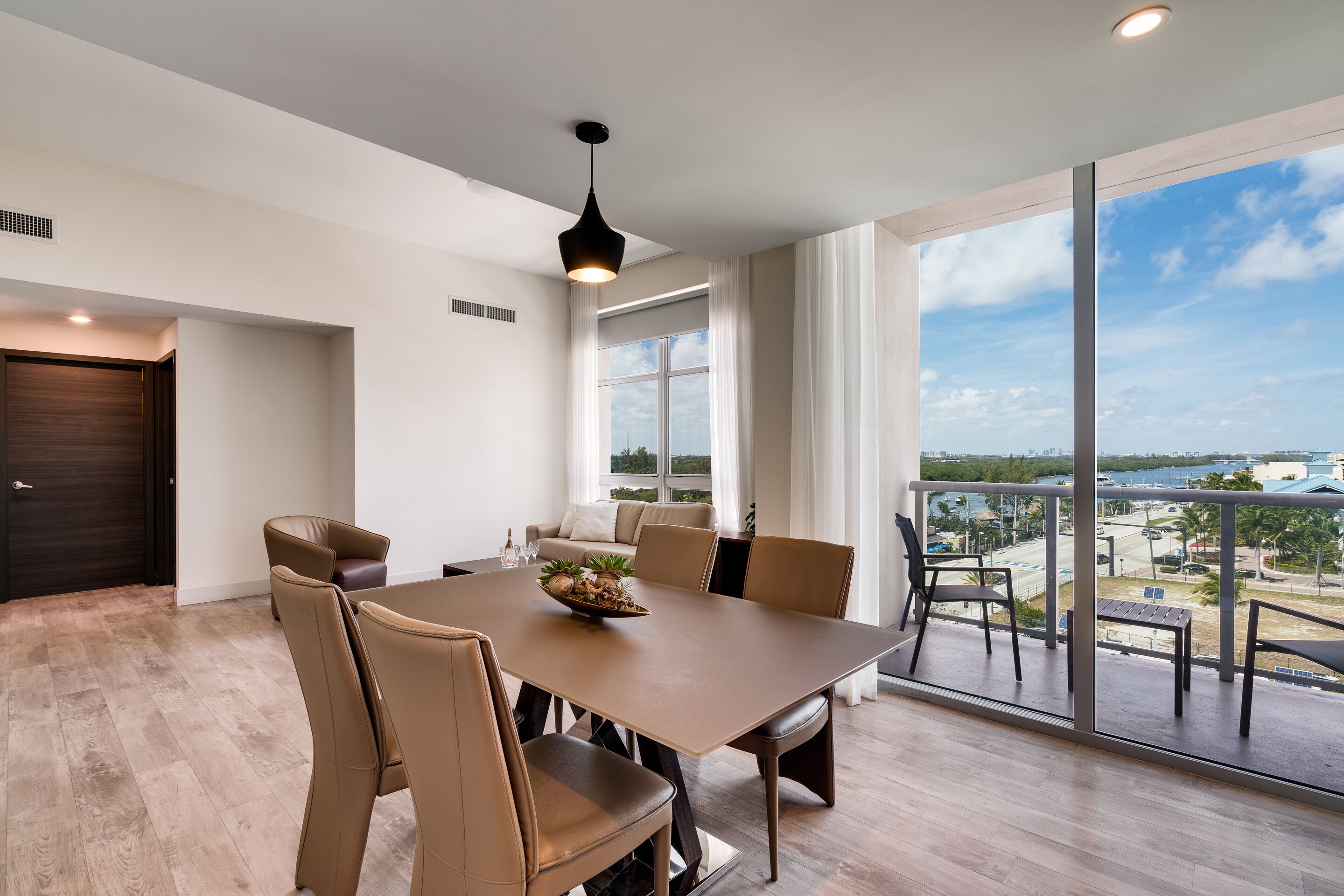Un amplio comedor con una mesa grande y sillas, una lámpara colgante moderna y vistas al exterior.