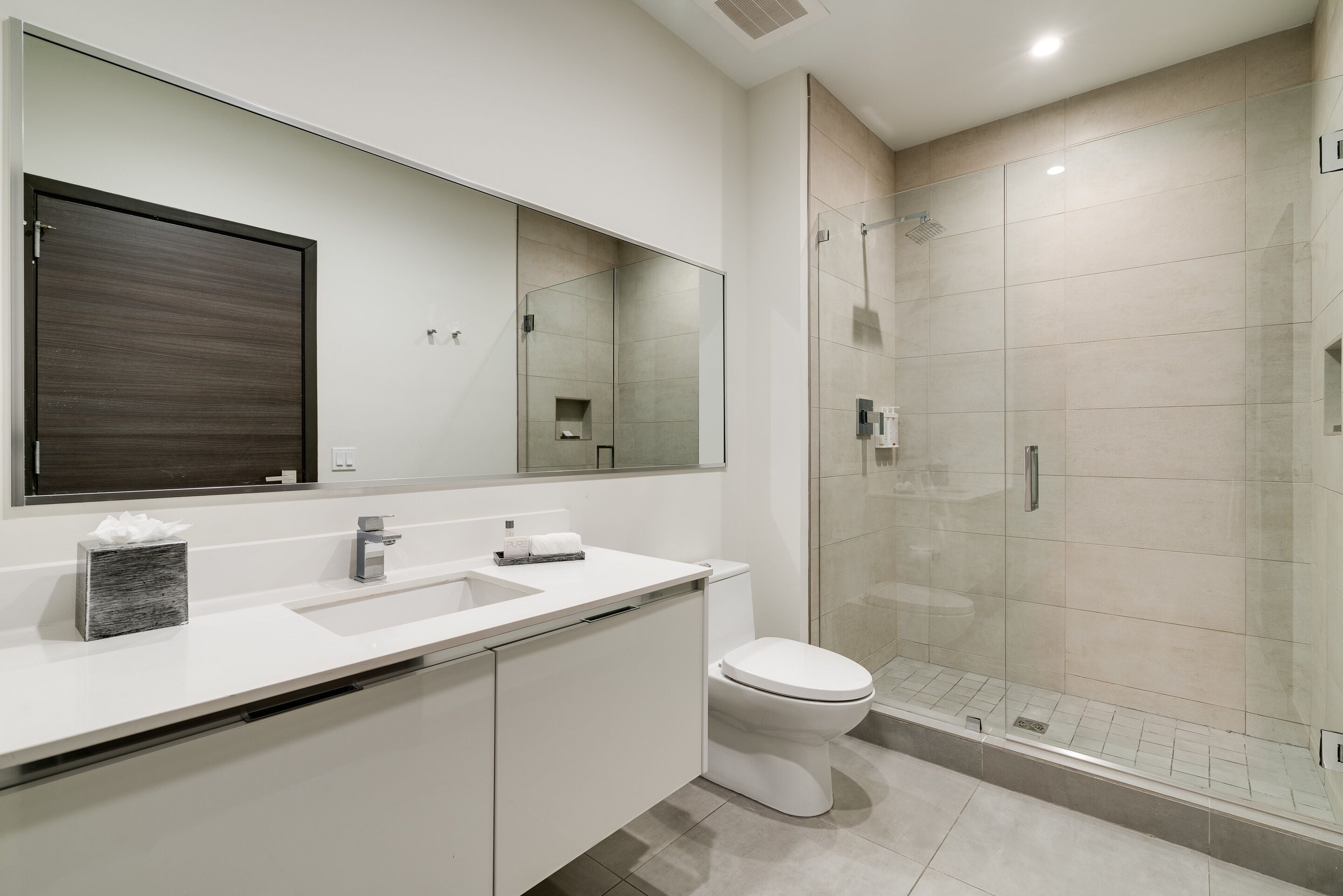 Une salle de bain moderne avec une douche à l’italienne en verre, un lavabo blanc et des toilettes.