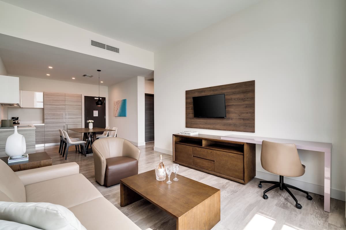 Un salon moderne comprenant un canapé, une table basse, un téléviseur et un coin repas avec des chaises et une table.