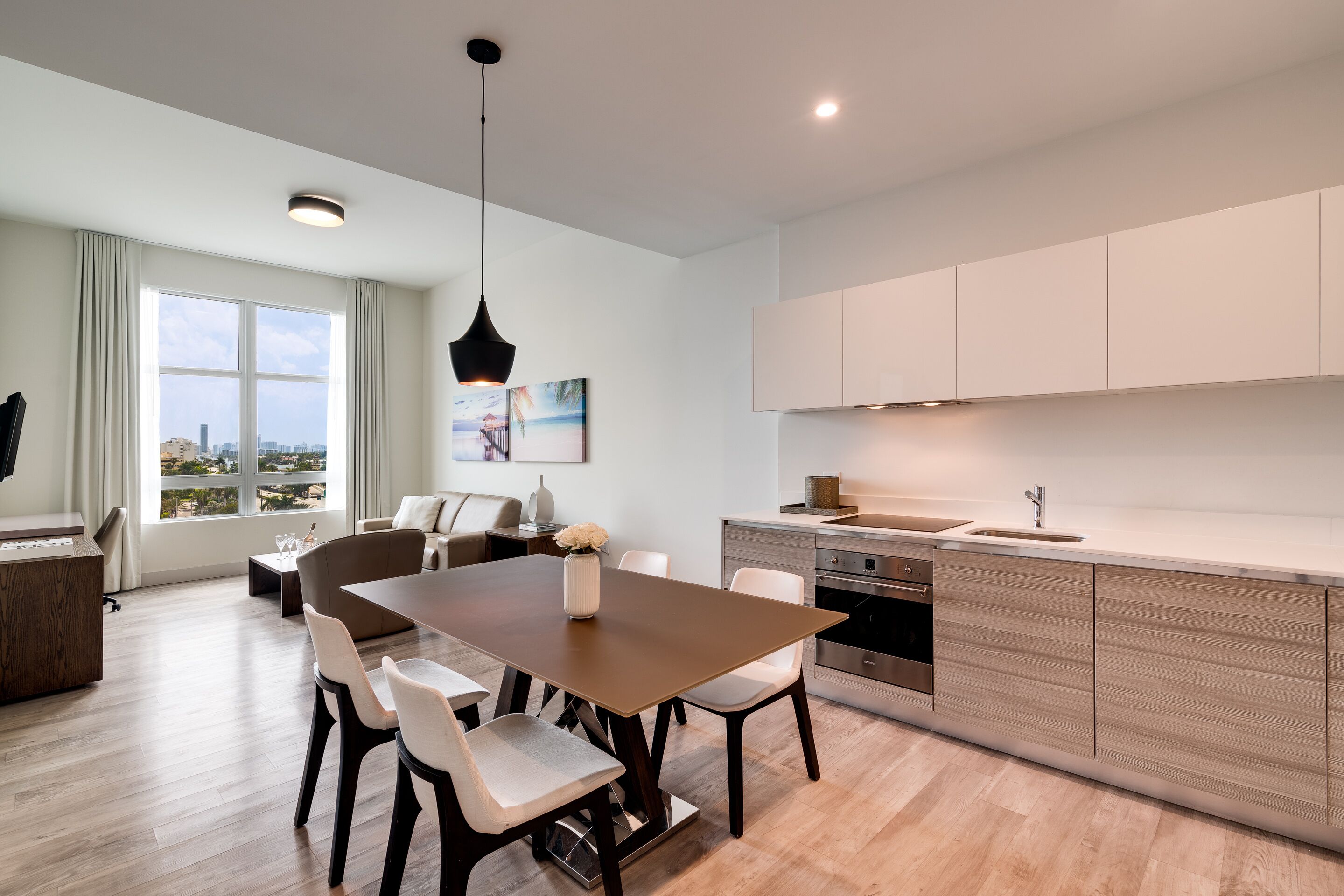 A modern kitchen with a wooden countertop, stainless steel appliances, and a dining area with a brown table and white chairs.