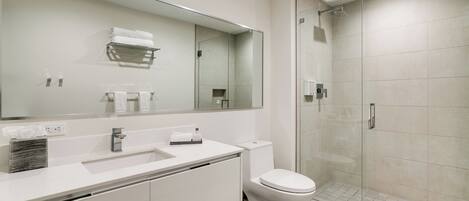 Un baño moderno con un espejo grande, lavamanos blanco y un inodoro.