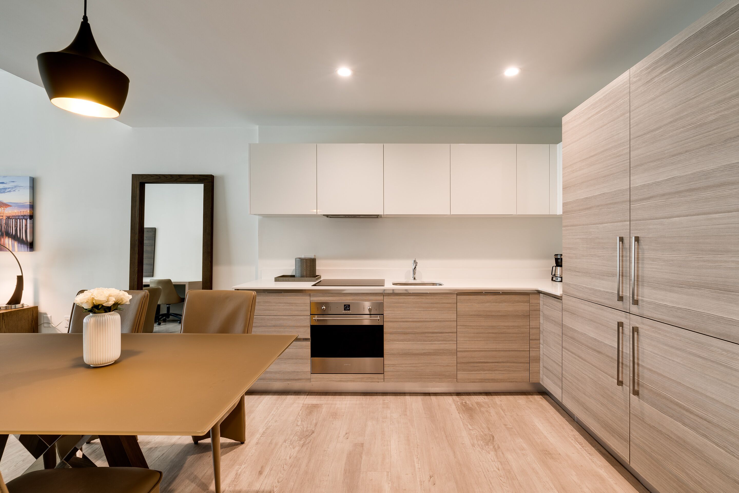 Cozinha moderna com bancada de madeira, eletrodomésticos de aço inoxidável e área de refeições com mesa e cadeiras.