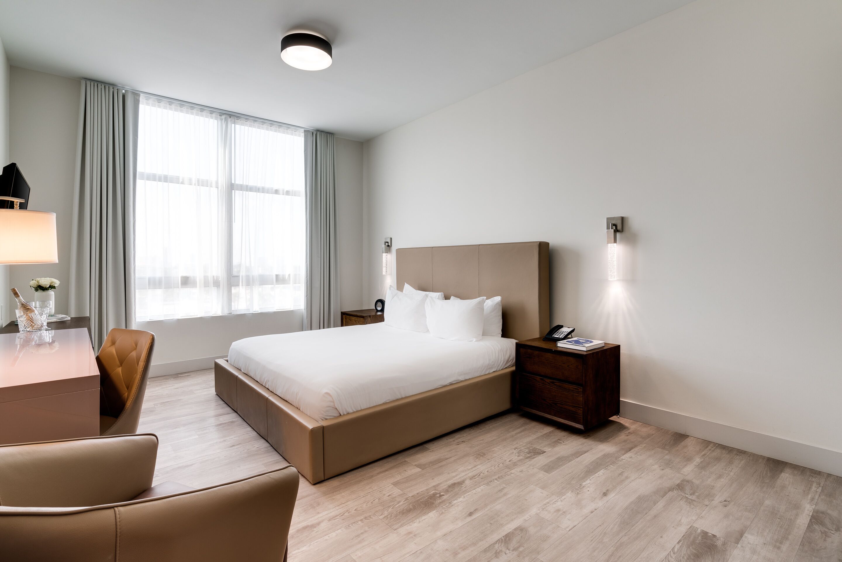 Habitación de hotel moderna con una cama grande, un escritorio con lámpara y una silla.