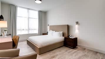 Habitación de hotel moderna con una cama grande, un escritorio con lámpara y una silla.
