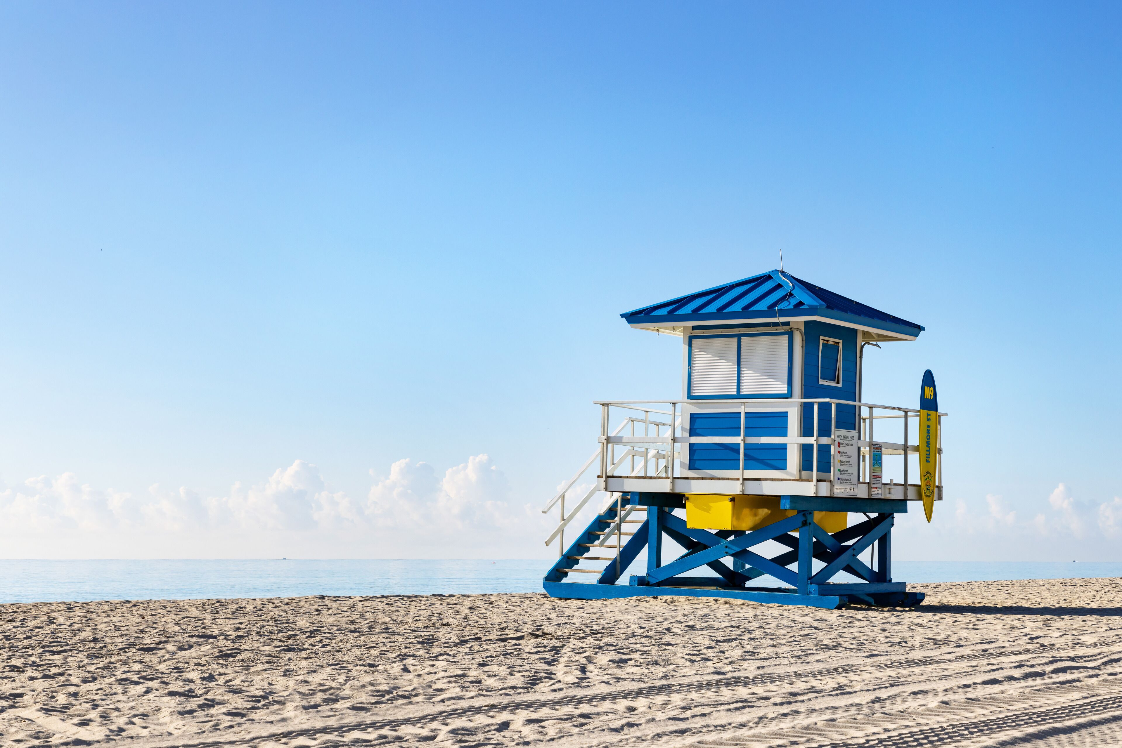 A lifeguard tower on a sandy beach with clear skies.