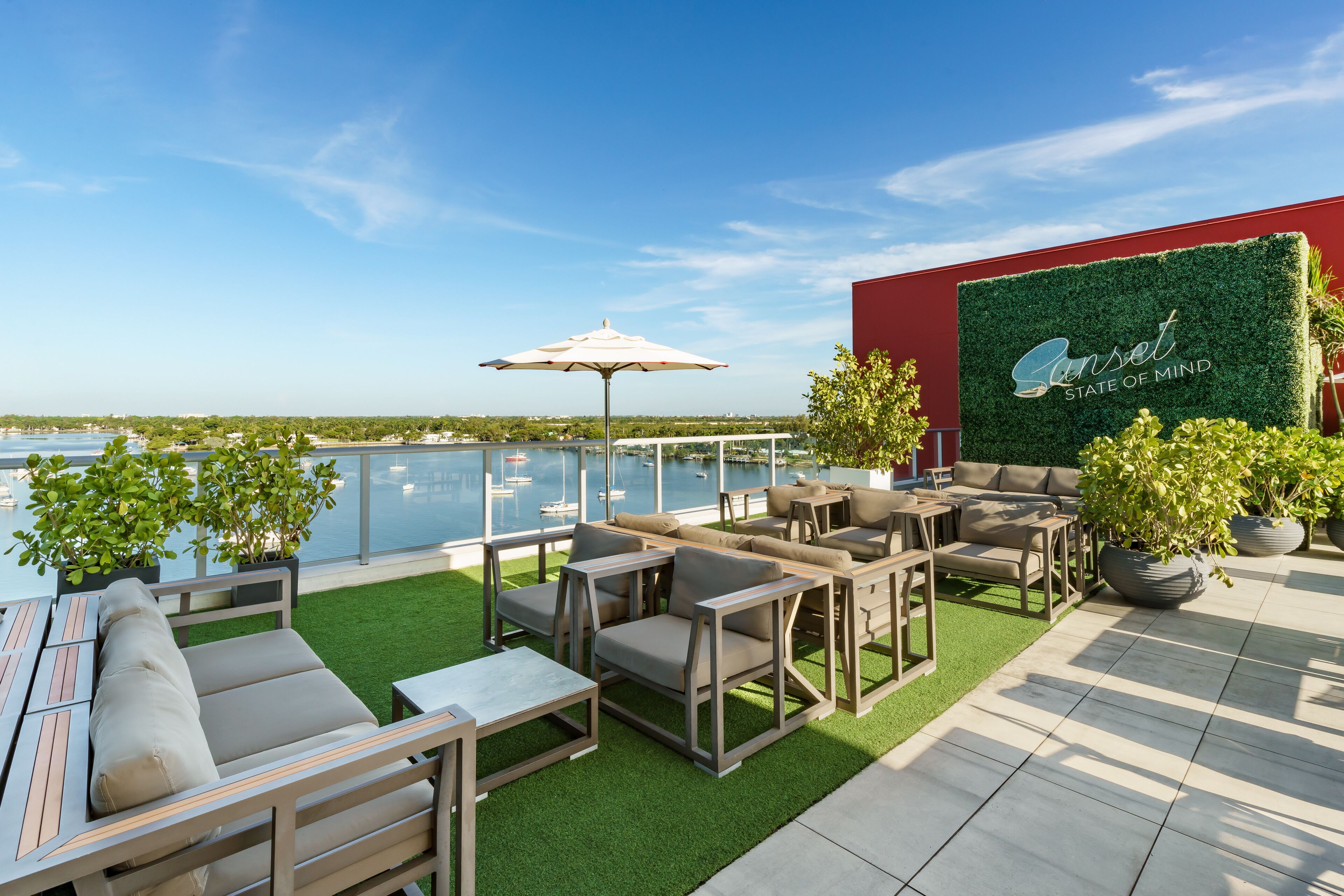 A rooftop patio with outdoor furniture, a view of the water, and a wall with the text "Sunset State of Mind".