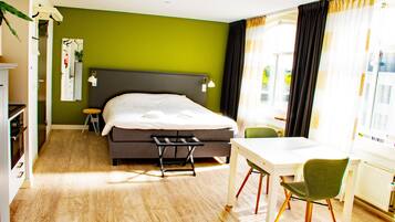 A hotel room with a bed, a desk, a chair, and a window with curtains.