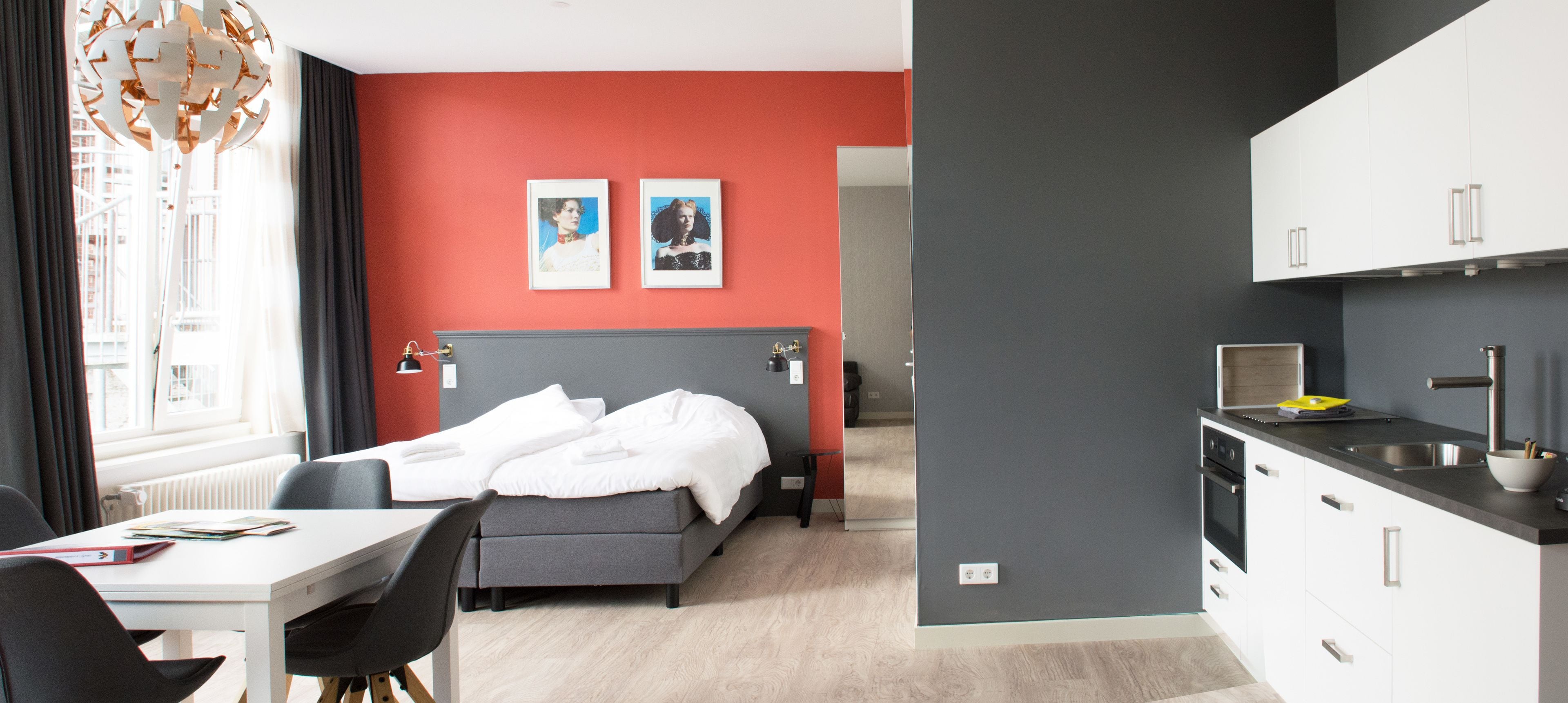 Een moderne hotelkamer met een bed, een eettafel en een kitchenette.
