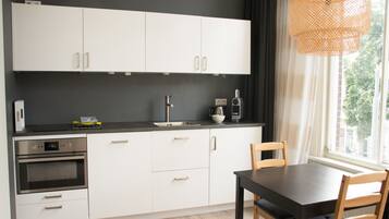 A modern kitchen with white cabinets, a black countertop, a built-in oven, and a dining table with chairs.