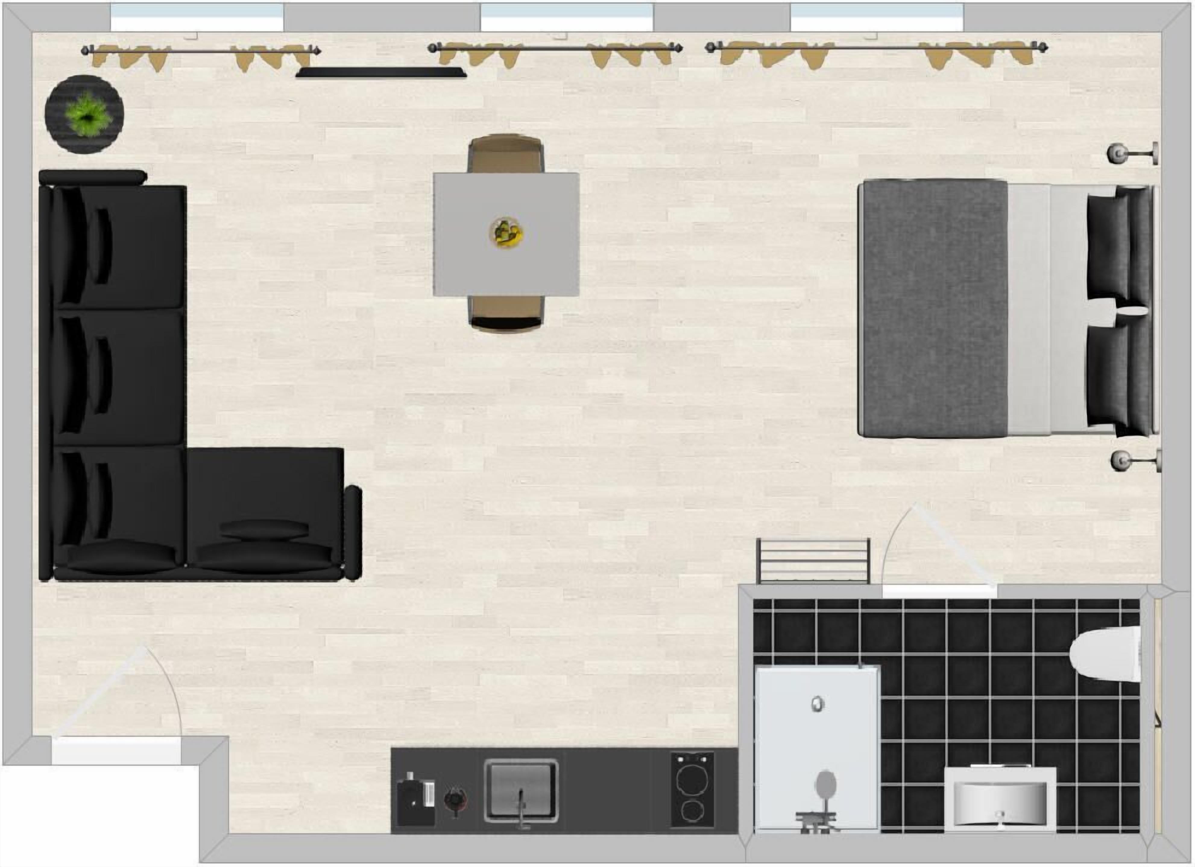 A hotel room layout with a sofa, a small table, a bed, a bathroom with a toilet and sink, and a small kitchen area.