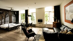 Een moderne kamer met een bed, een bureau, een stoel, een bank en een televisie.