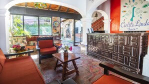 Eine Hotellobby mit einem Holzbüro, einem roten Sofa und einem großen Fenster mit Blick ins Freie.