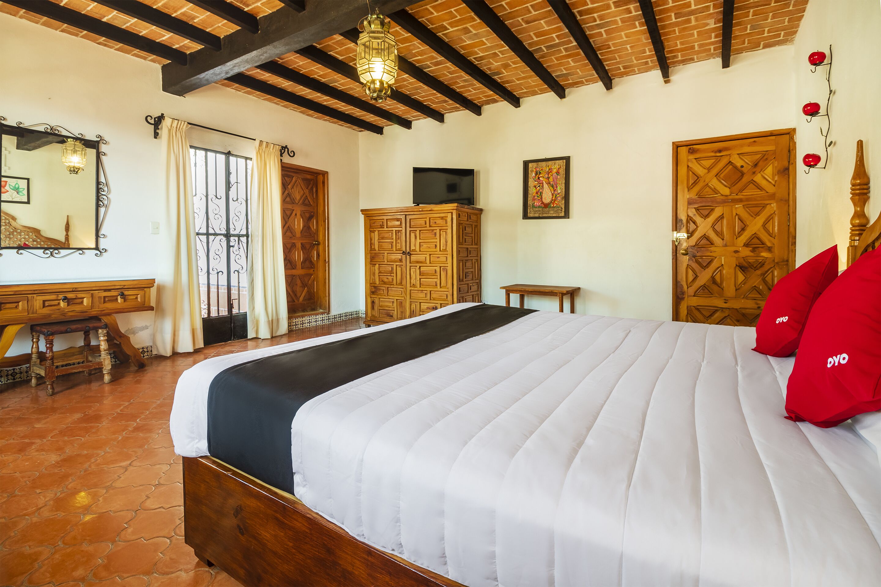 Un dormitorio con una cama grande, un armario de madera y un televisor en la pared.