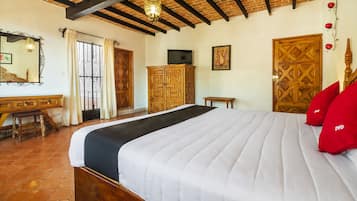 Un dormitorio con una cama grande, un armario de madera y un televisor en la pared.