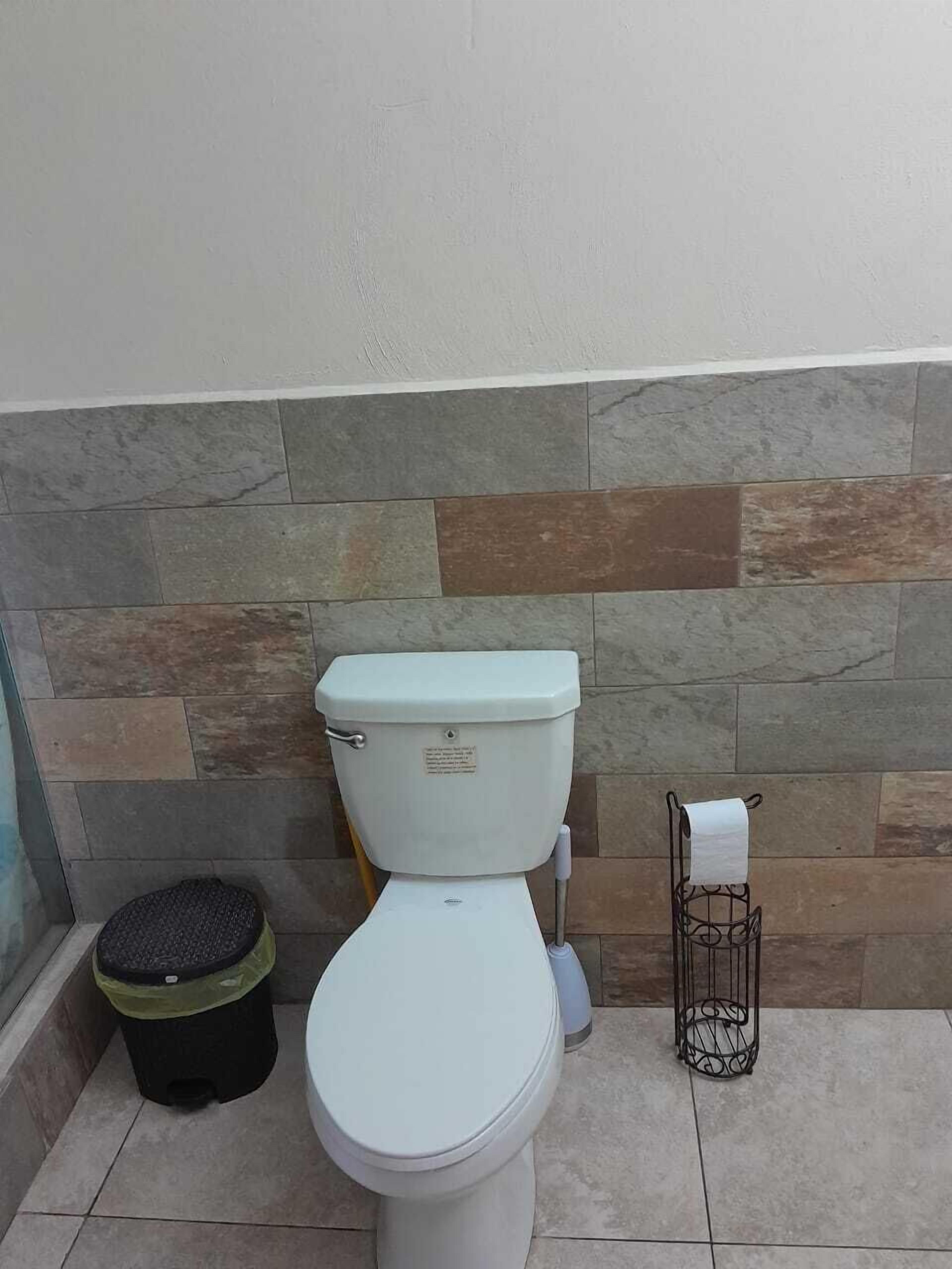 A toilet in a bathroom with a stone wall and tiled floor.